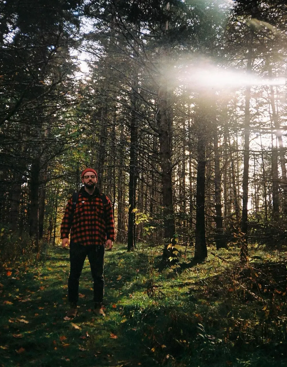 Portrait of Dylan James standing in a forest.